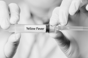 Yellow Fever injection is held between the fingers of two hands. The words Yellow Fever are written across the injection.